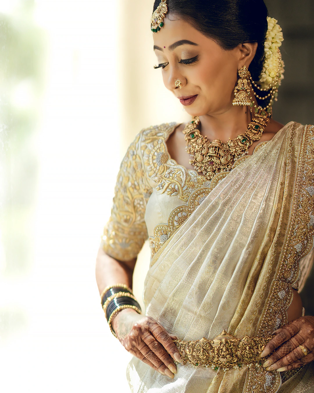 Rashmitha in a gold-worked bridal saree, photographed in natural window light